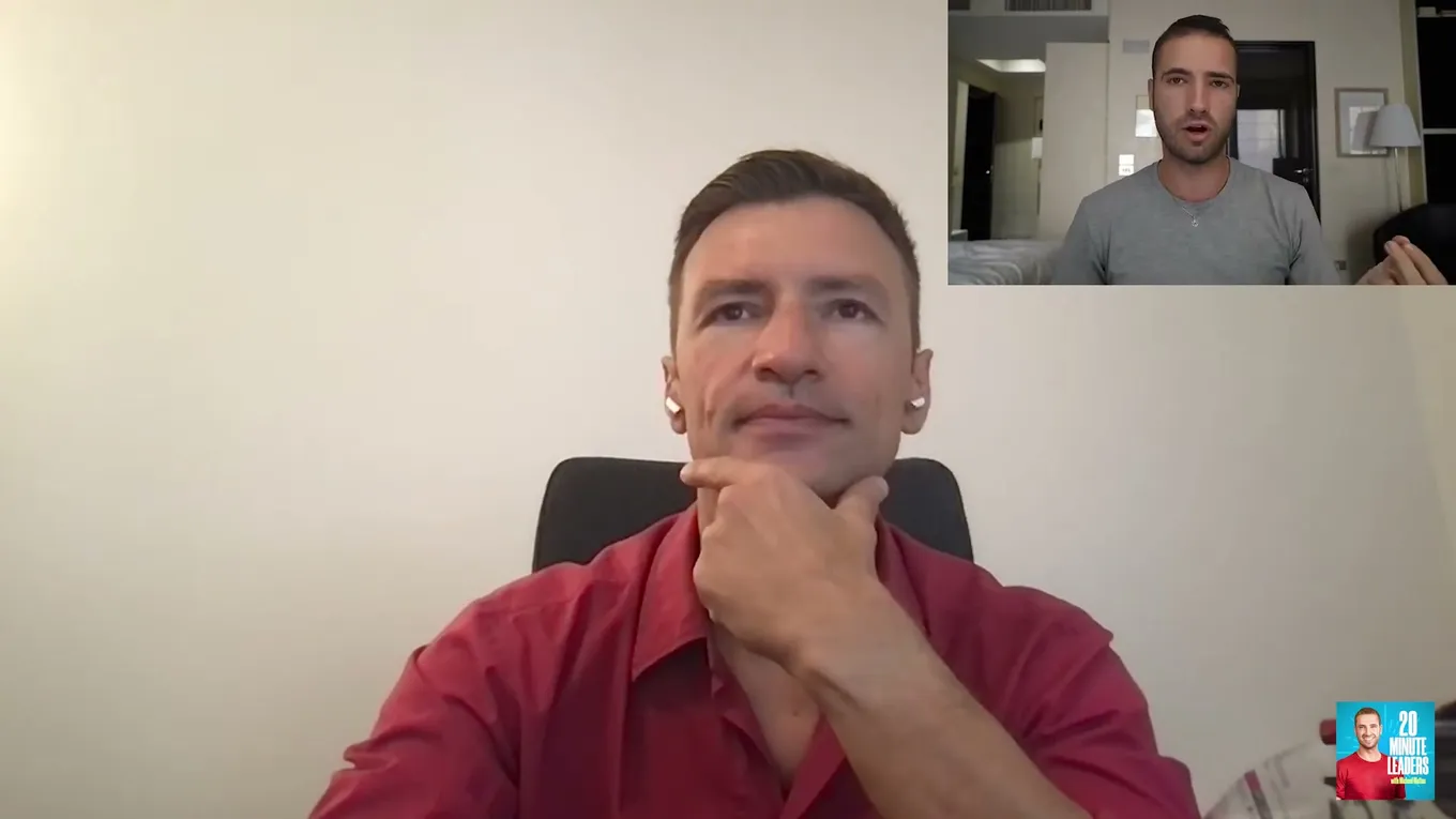 Marius Hanganu, în cămașă roșie, cu mâna la bărbie, ascultă în timpul unui interviu prin apel video, cu gazda într-o fereastră mică în colțul din dreapta sus.
