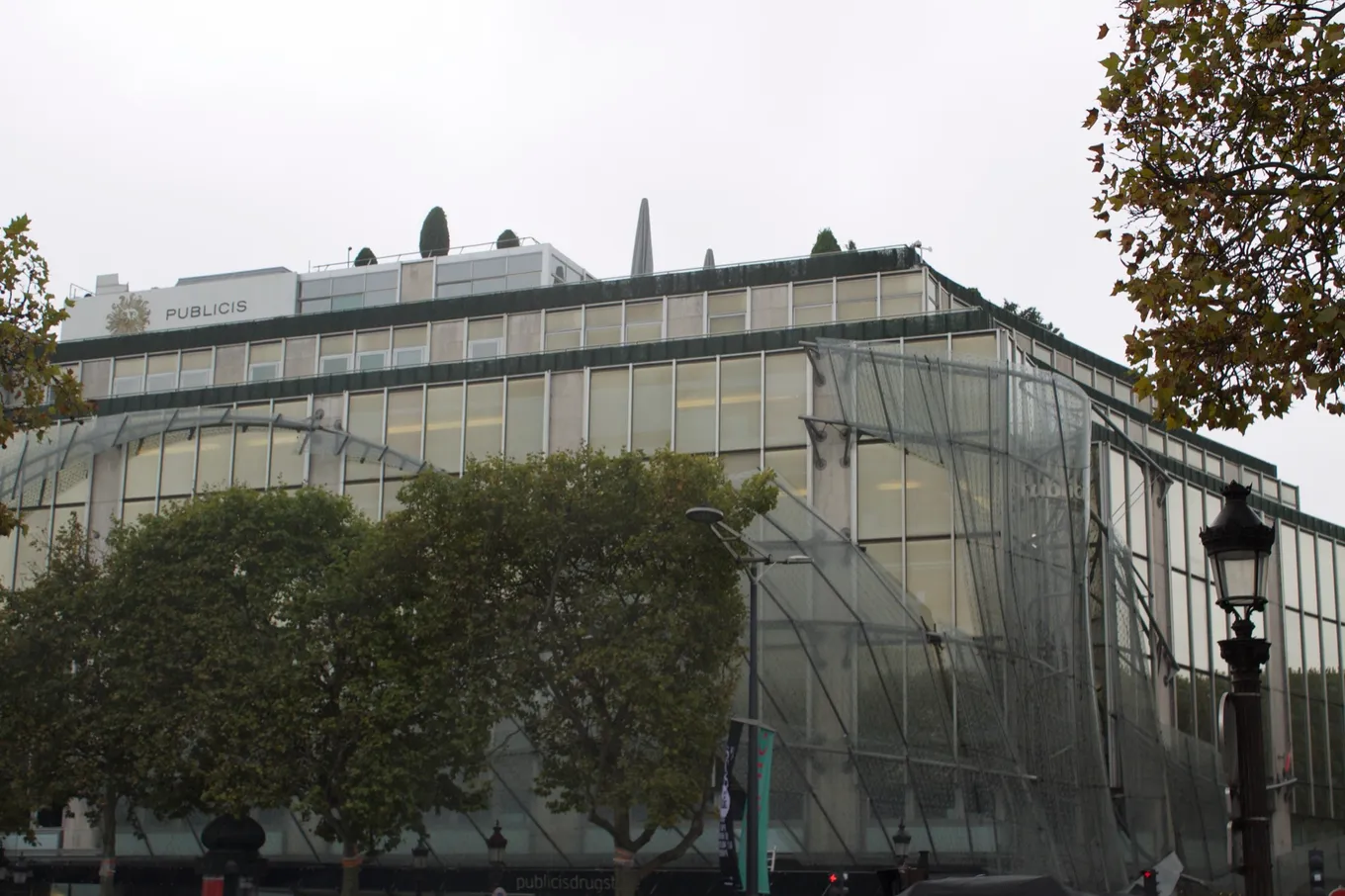 Clădirea Publicis de pe Champs-Élysées, Paris, cu fațada de sticlă și firma Publicis pe acoperiș.