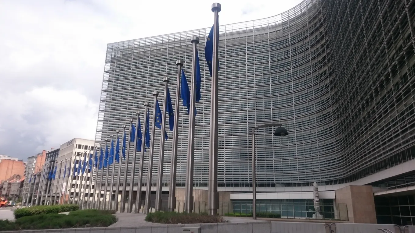Clădirea Berlaymont din Bruxelles, sediul Comisiei Europene, cu un șir de steaguri ale UE în față.